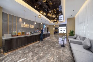 Een hotel receptie met een marmeren vloer, een receptiebalie, een bank en een groot raam.