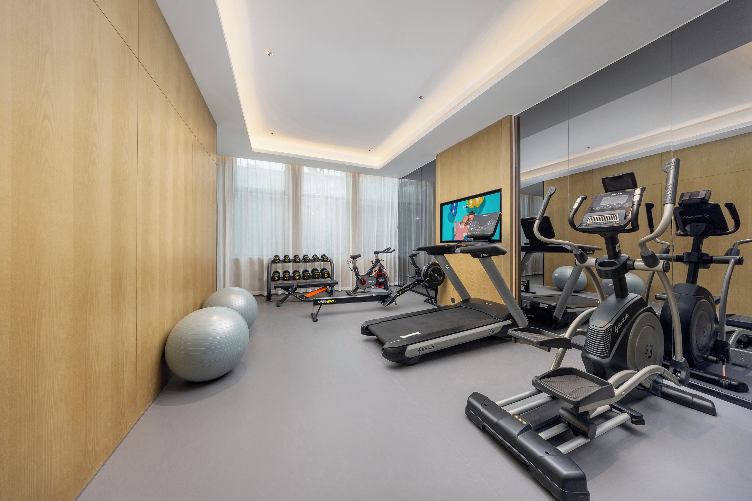 A modern gym with cardio equipment, weight machines, and exercise balls.