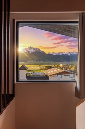 Una ventana con vista a una cordillera y un pueblo abajo.