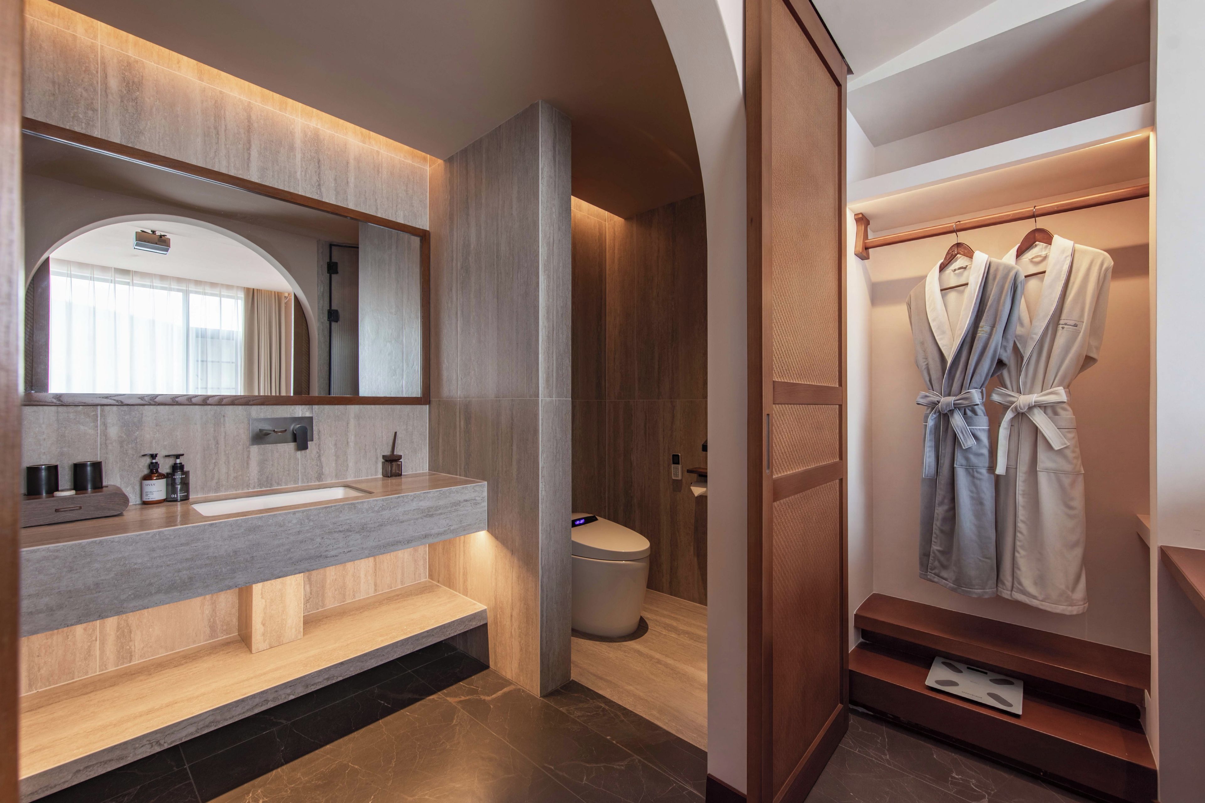A modern bathroom with a vanity, a toilet, and a robe rack.
