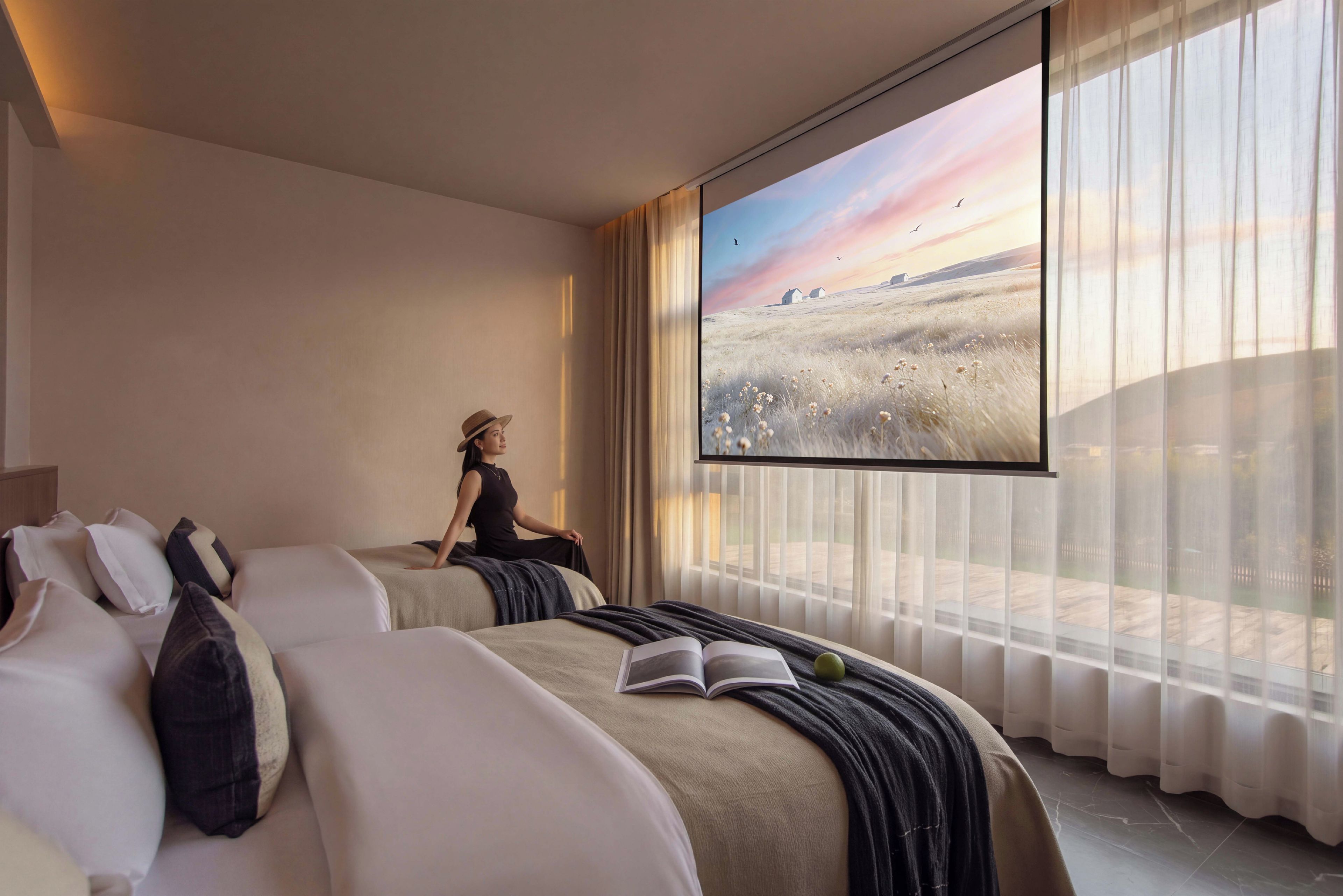 A hotel room with a large window, a bed, a chair, and a book.