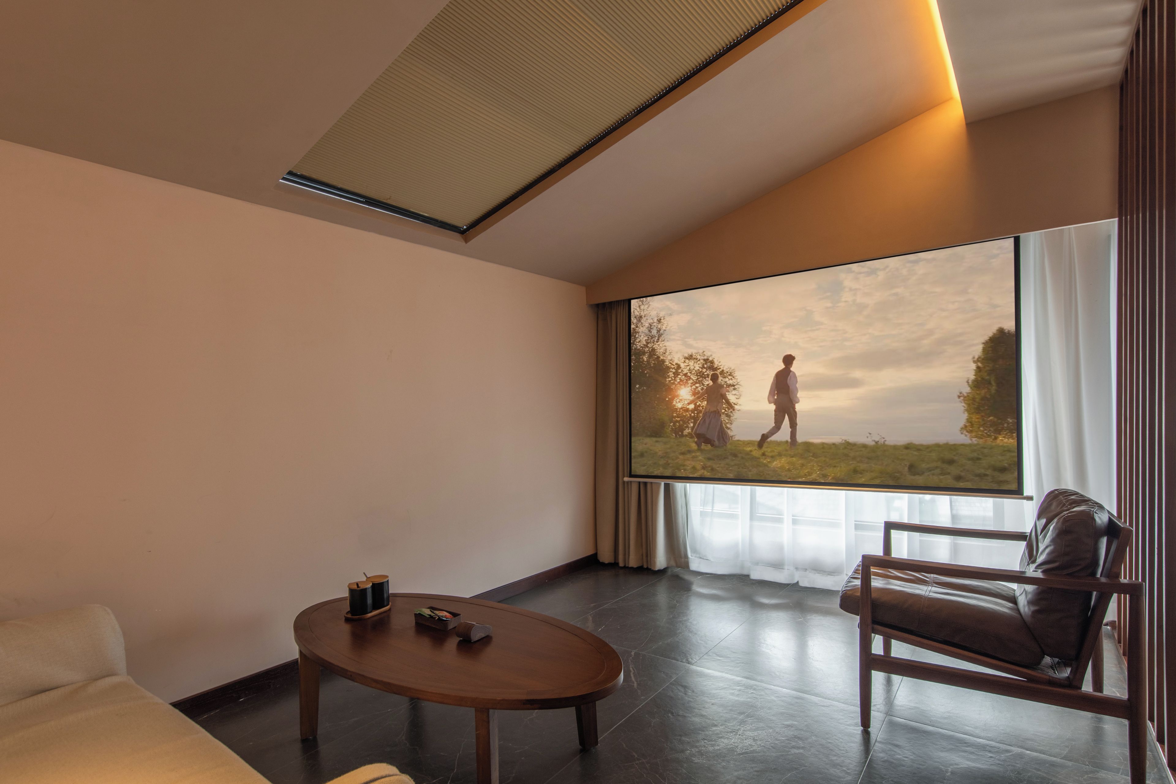 Et moderne hotelværelse med et stort vindue, en sofa, et sofabord og en læderlænestol.