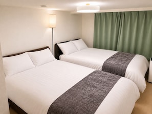 Ein Hotelzimmer mit zwei Betten, einem Nachttisch, einer Lampe und einem grünen Vorhang.