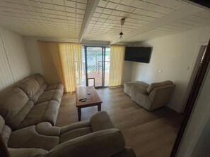 A living room with a sofa, a coffee table, and a television mounted on the wall.