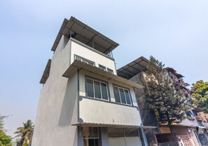 Un edificio de varios pisos con techo plano y un balcón en el último nivel.