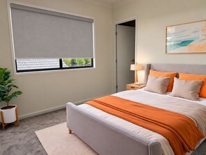 Una camera da letto con un letto, un comodino, una lampada, una finestra con persiane, una pianta e un quadro appeso al muro.