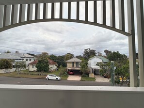 En boligvej med huse, en hvid bil parkeret langs vejen, og en klar himmel.