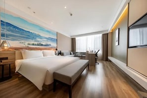 Ein modernes Hotelzimmer mit einem großen Bett, einem Schreibtisch und Blick auf eine gebirgige Landschaft.