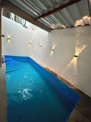 A swimming pool with a blue floor, surrounded by white walls and equipped with wall-mounted lights. - New Listing (Tolima)