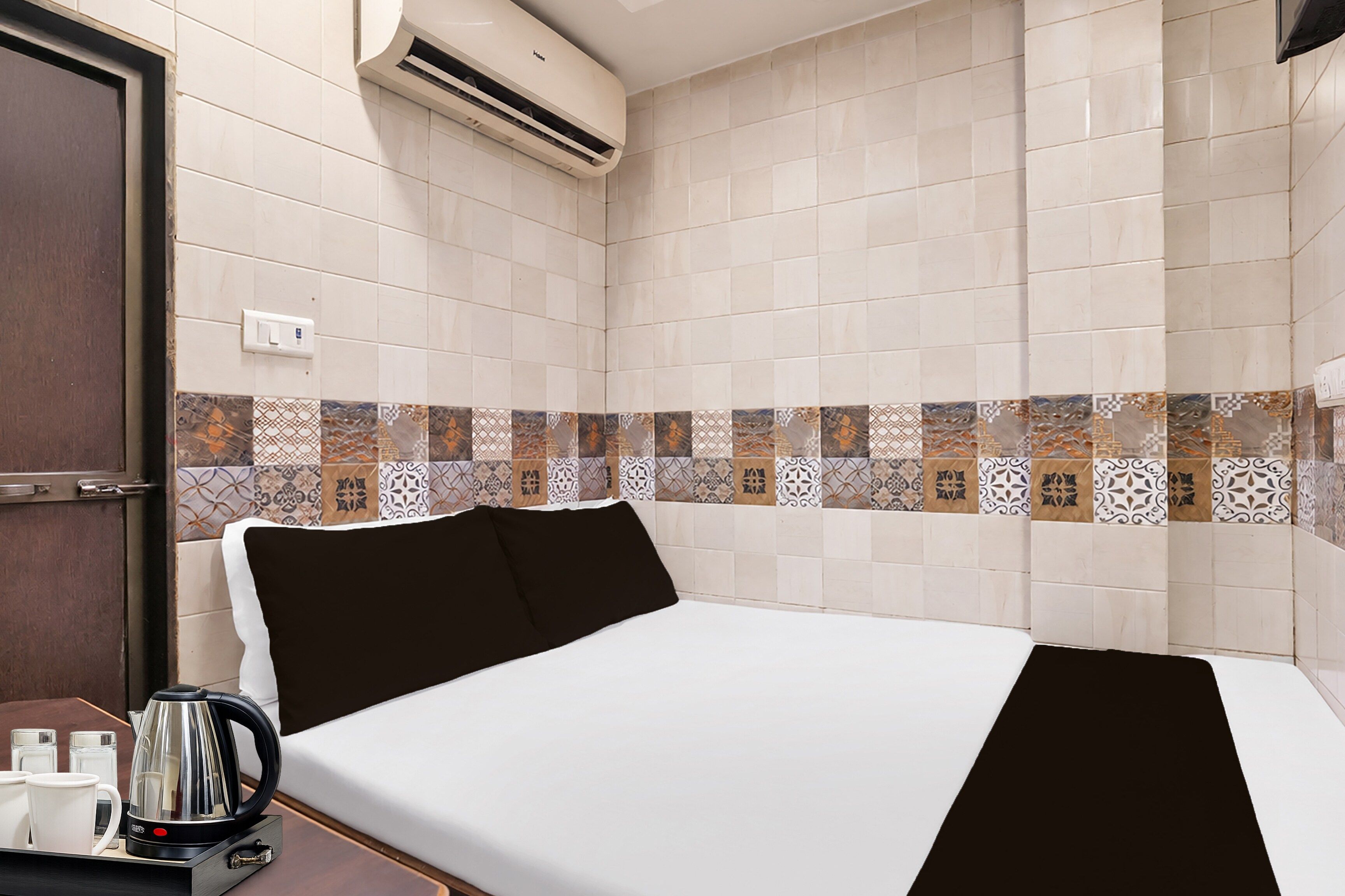 A hotel room with a bed, a coffee maker, and a wall-mounted air conditioner.