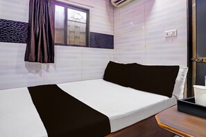 A single bed with a white and black bedspread, a window with a curtain, and a wall with a patterned tile design. - HOTEL O CU LODGING (Mumbai)