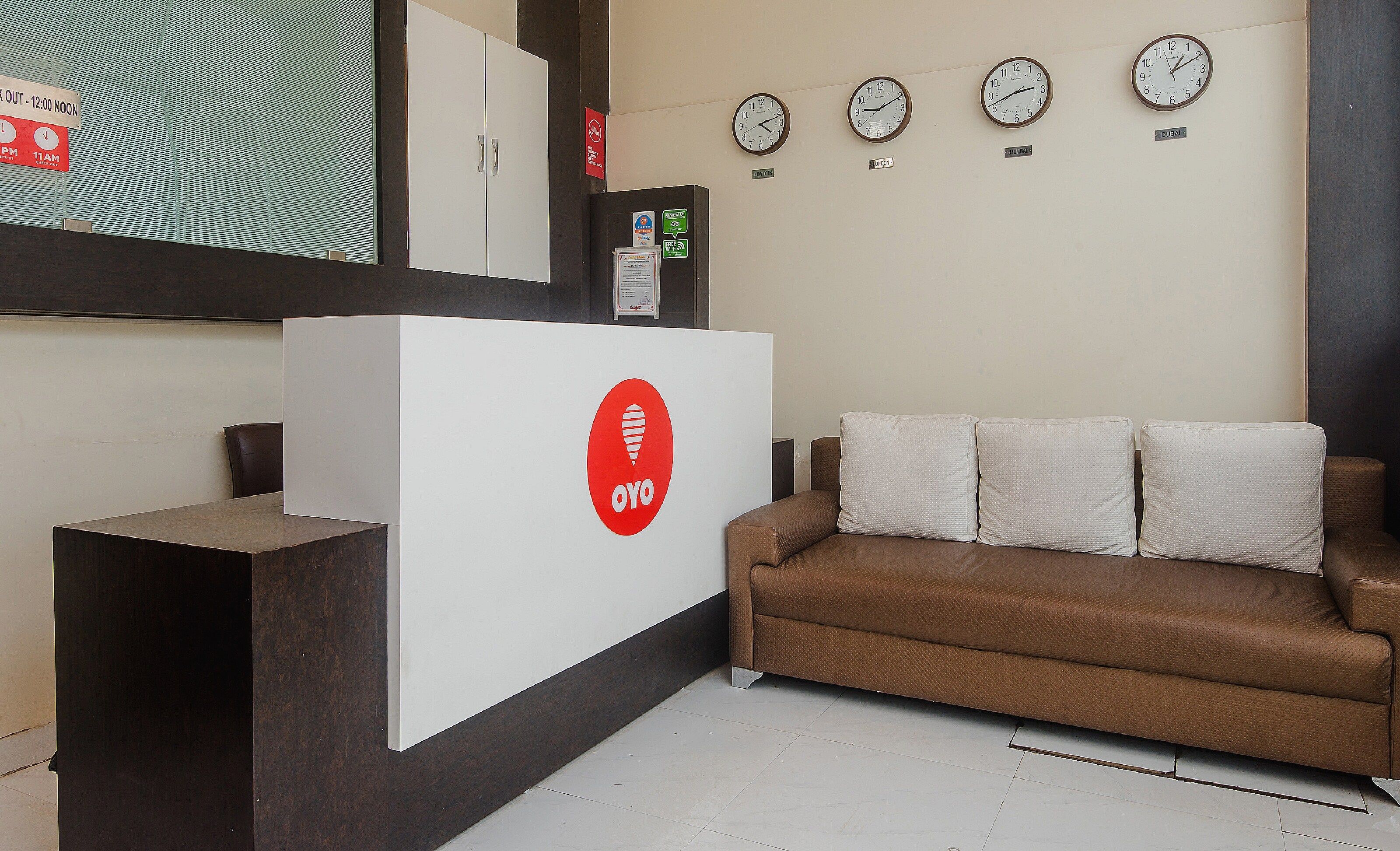 A reception area with a reception desk, a brown sofa, and three wall clocks.