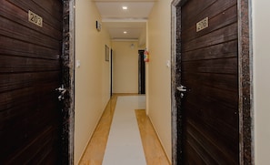 A corridor with two doors, each marked with a number. The corridor has a tiled floor and a plain wall. - Hotel O Alfa Grand (Mumbai)