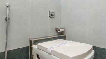 A bathroom with a white toilet, a shower, and a towel rack.