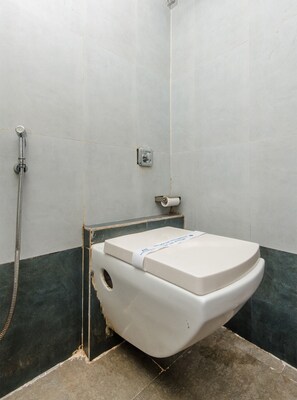 A bathroom with a white toilet, a shower, and a towel rack. - Hotel O Alfa Grand (Mumbai)