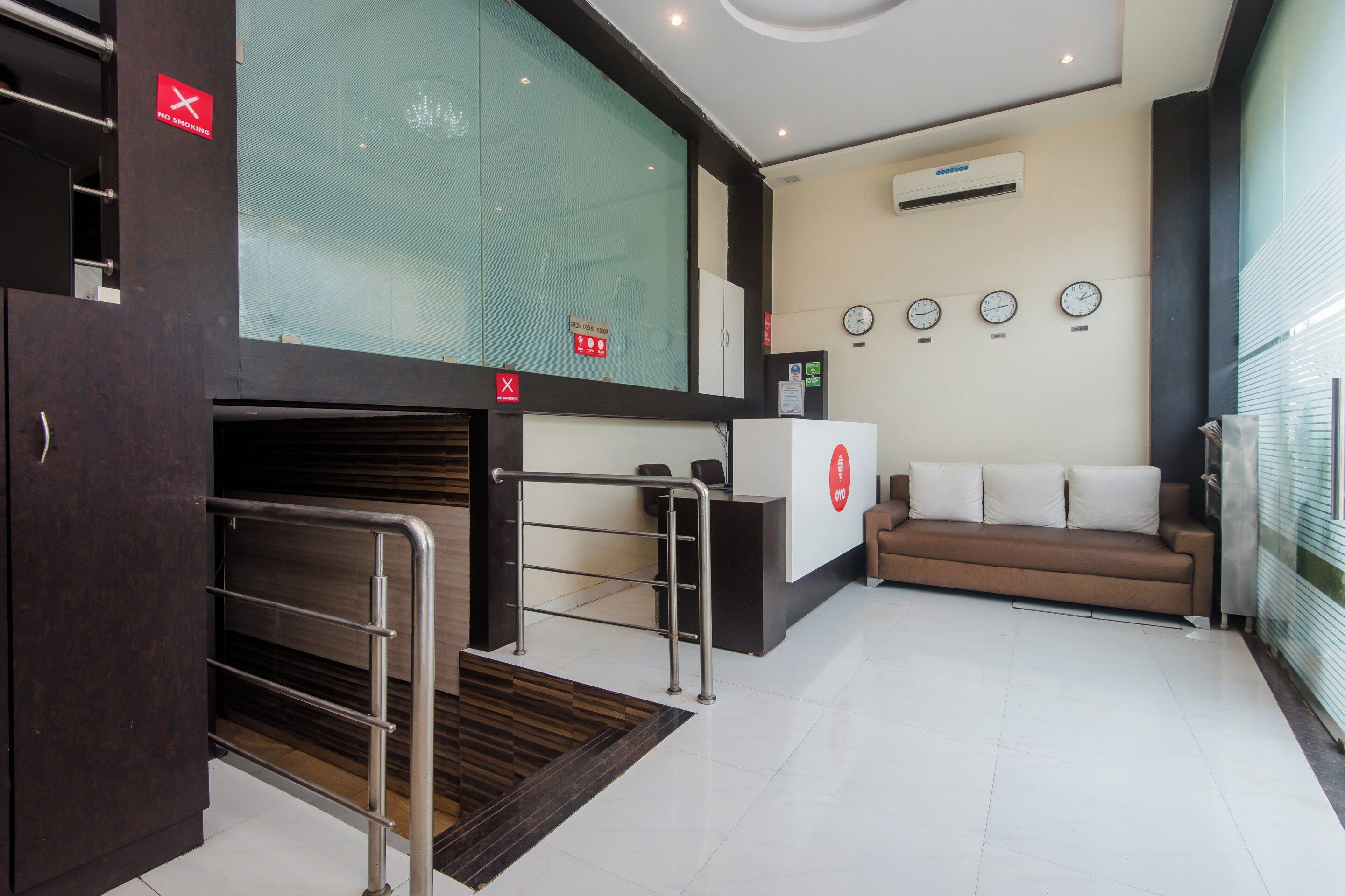 A hotel lobby with a reception desk, a sofa, and a wall with clocks.