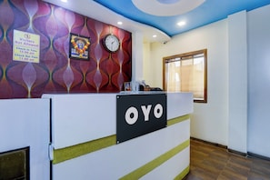 A reception desk with a clock and a sign indicating check-in and check-out times.