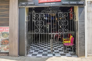 A restaurant entrance with a checkered floor and a metal gate.