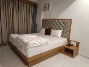 A hotel room with a bed, a bedside table with a phone, and a wall-mounted air conditioning unit. - Hotel O The Lions Hotel (Badlapur Thane)