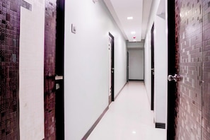 A hallway with doors on both sides, a tiled floor, and a light-colored wall. - Townhouse Asalpha Near International (Mumbai)