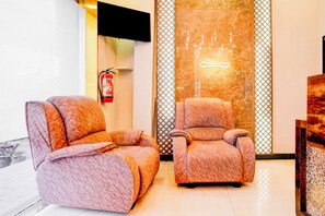 Two plush armchairs in a modern lobby with a fire extinguisher mounted on the wall. - Townhouse Asalpha Near International (Mumbai)