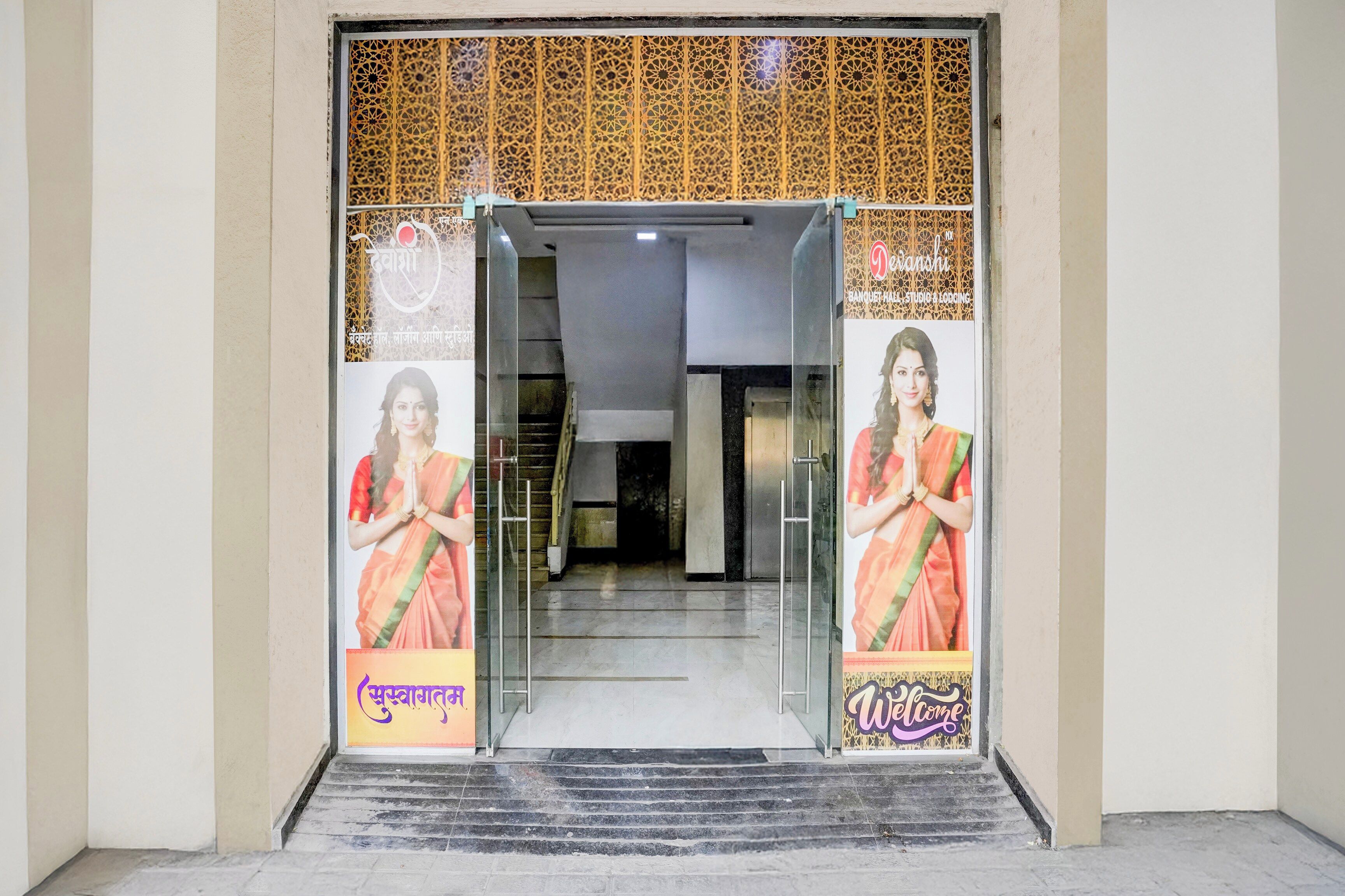 A hotel entrance with a glass door, a staircase leading inside, and a decorative wall with a geometric pattern.