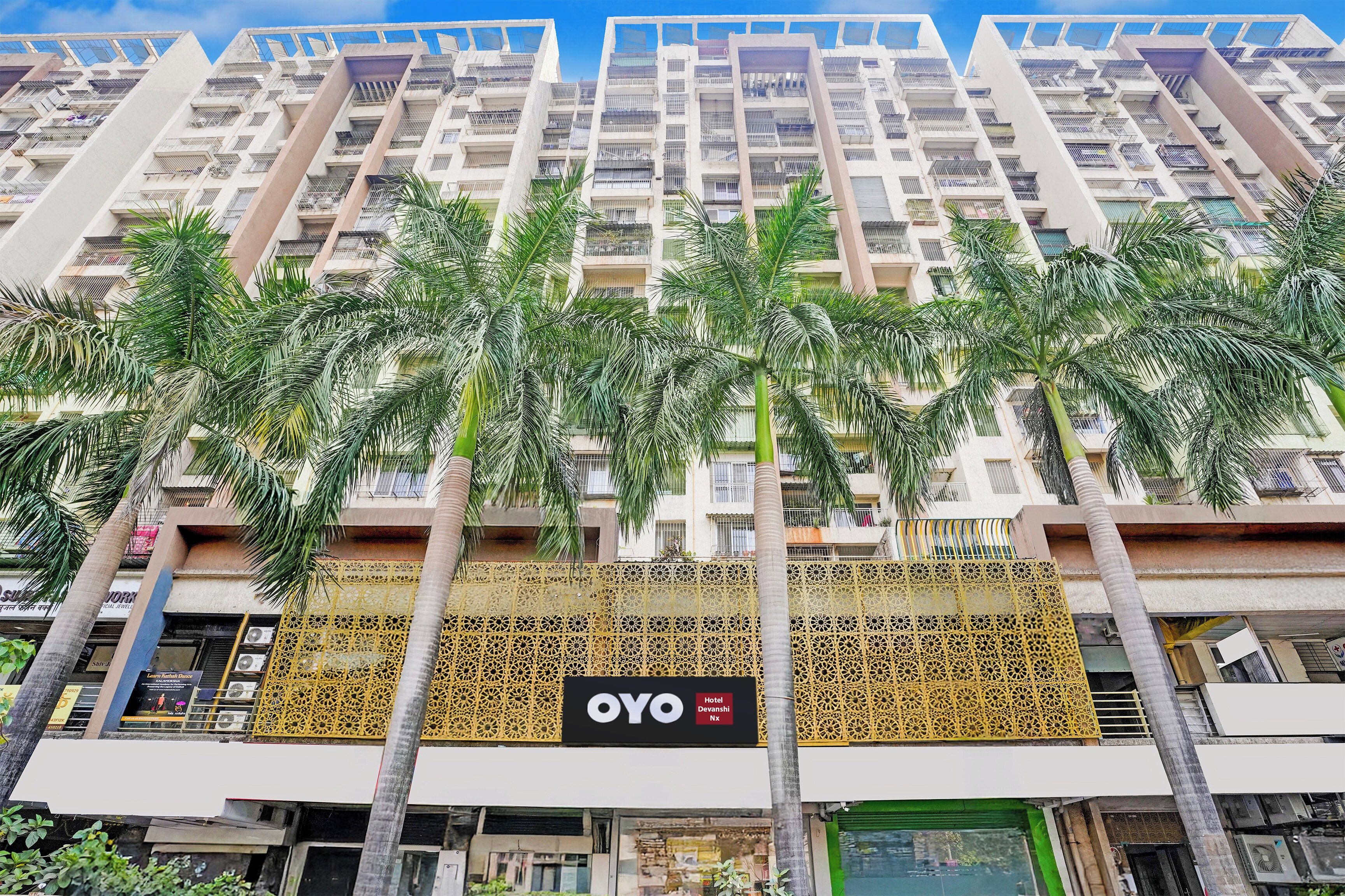 A multi-story hotel with balconies, palm trees, and a decorative facade.