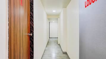 Un pasillo con una puerta de madera marcada con el número 1, una pared gris con la palabra 'LODGING' en rojo y un piso de baldosas.
