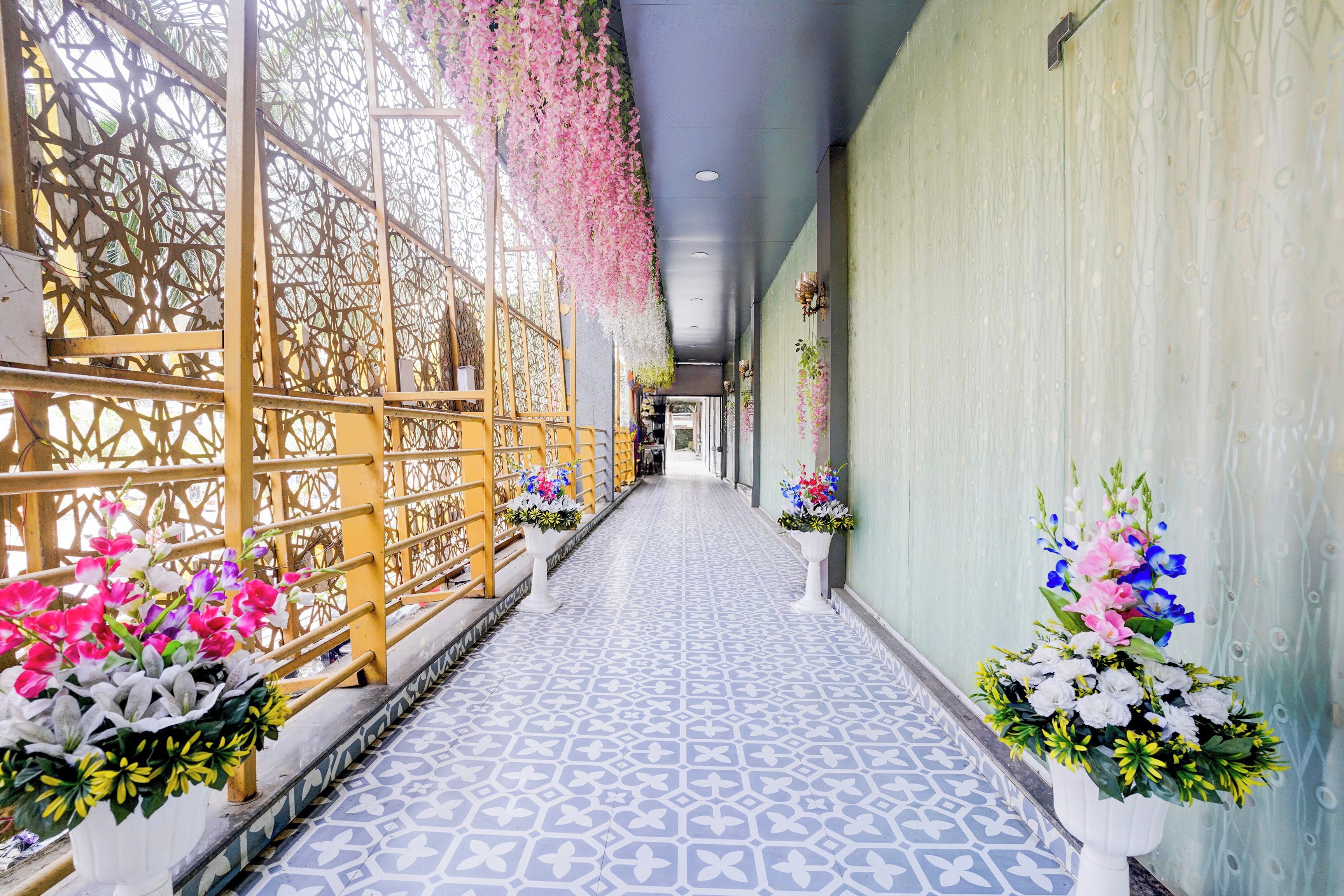 Un pasillo con suelo estampado, barandillas decorativas y arreglos florales.