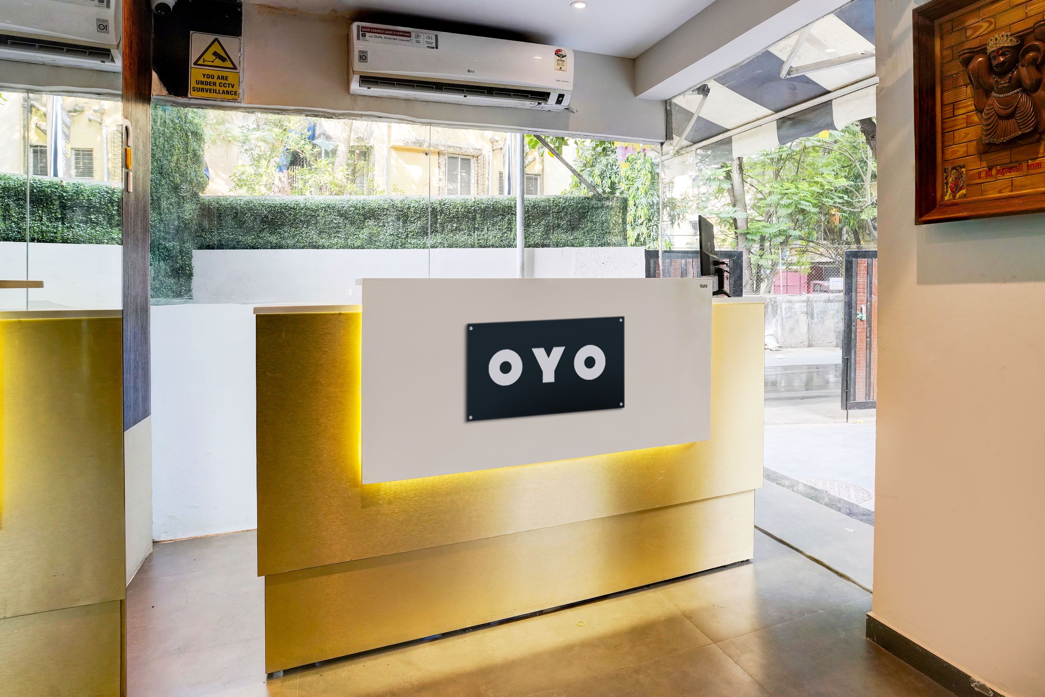 A reception desk with a sign that reads 'OYO' and an air conditioning unit above it.