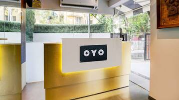 Una mesa de recepción con un letrero que dice 'OYO' y una unidad de aire acondicionado arriba.