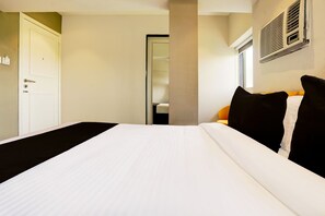Una habitación de hotel con una cama, una puerta y una ventana.