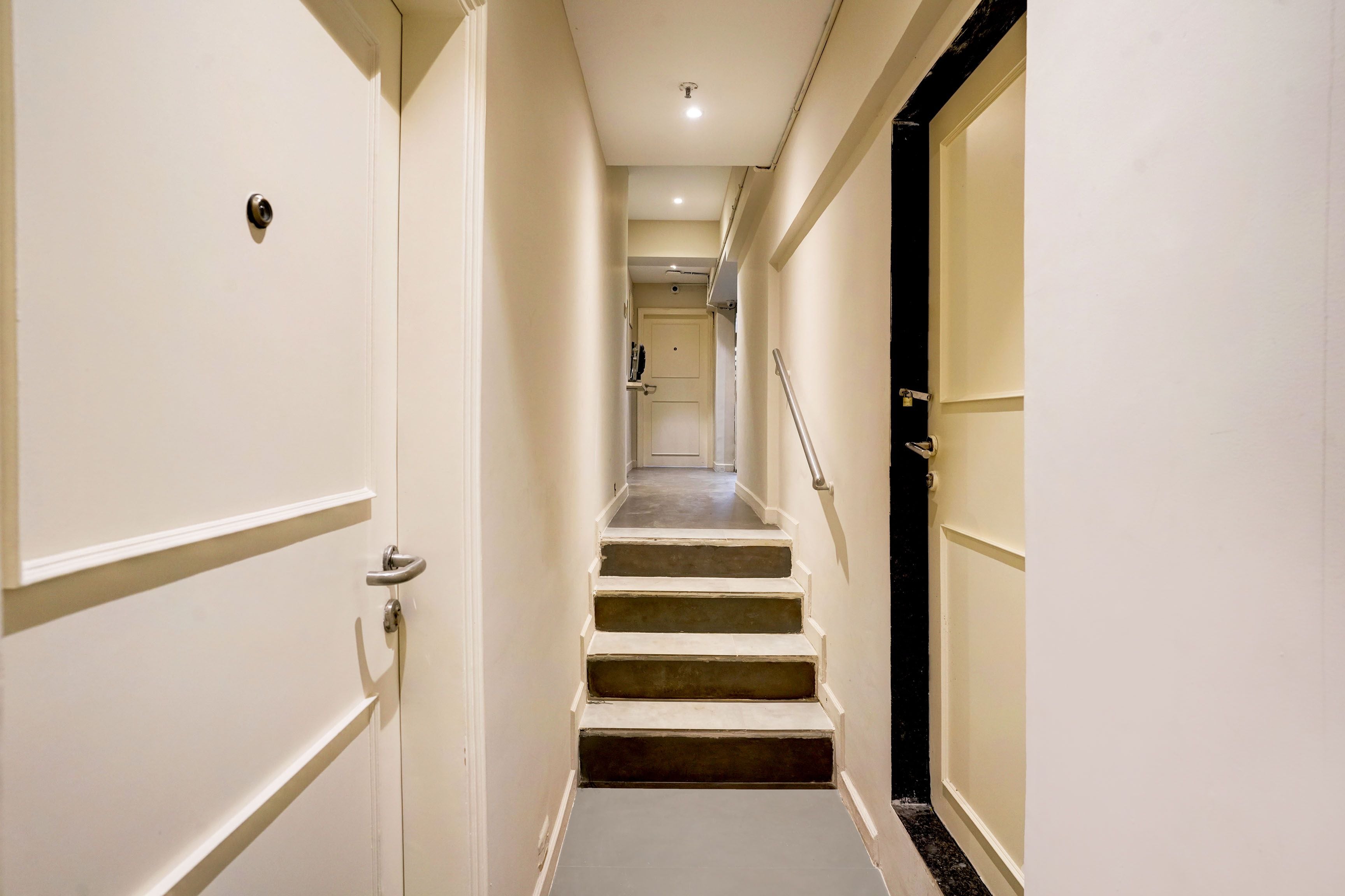 A narrow hallway with a staircase leading to a door at the end.