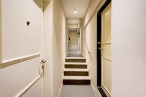 Un pasillo estrecho con una escalera que lleva a una puerta al final.