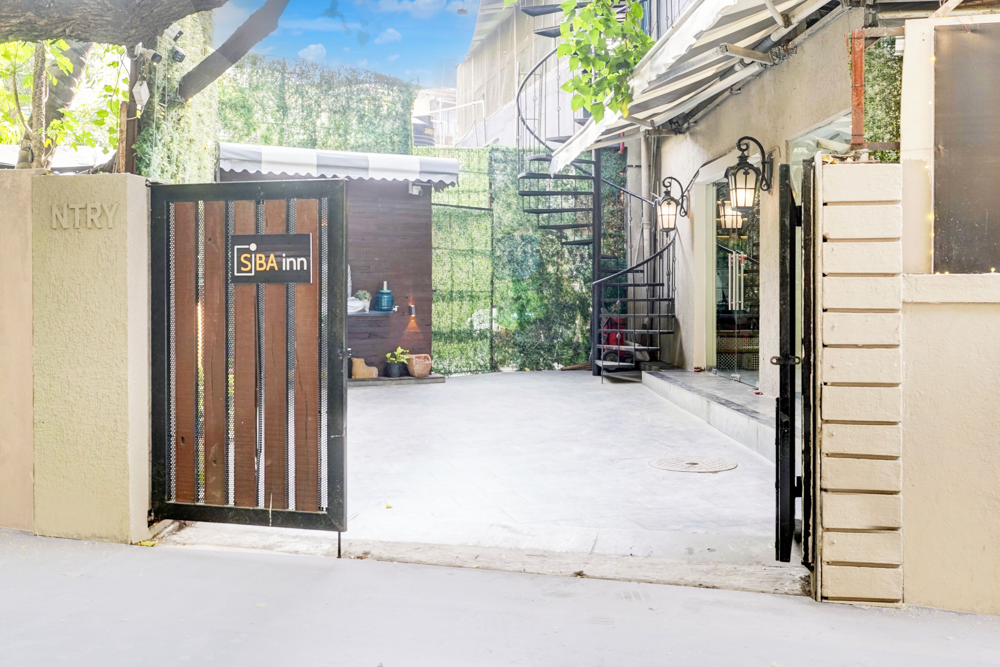 A gated entrance to a property with a sign for 'SIBA inn' and a visible staircase leading to a building.