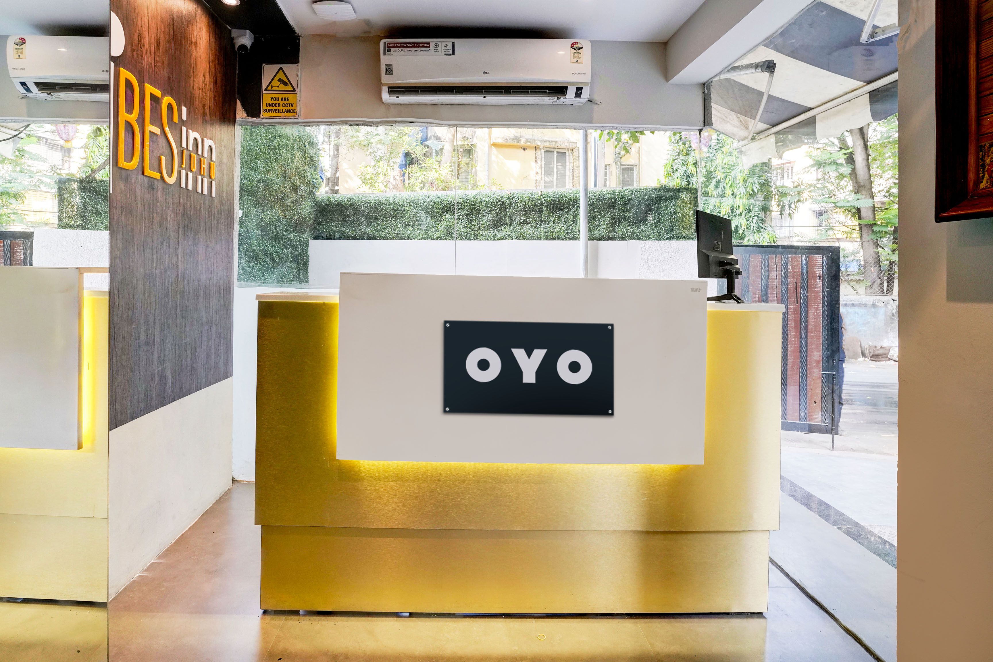 A reception desk with a sign that reads 'OYO' and a sign above it stating 'YOU ARE UNDER CCTV SURVEILLANCE'.