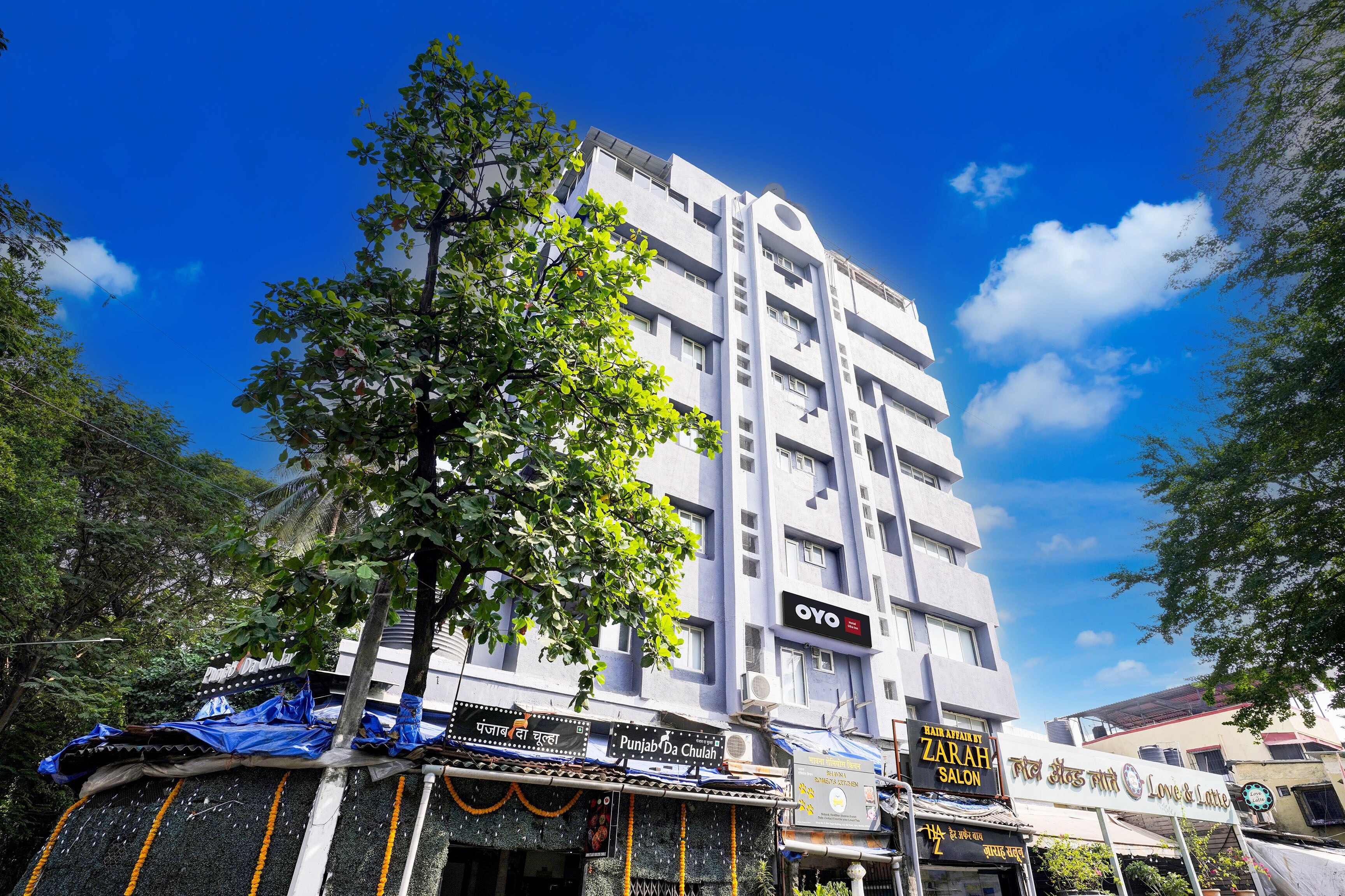 A multi-story building with commercial establishments on the ground floor, including a salon and a restaurant.