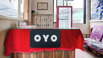 A reception desk with a red tablecloth, a sign reading 'OYO', and a calendar on the wall.