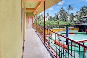 A balcony with a view of a pool and palm trees.