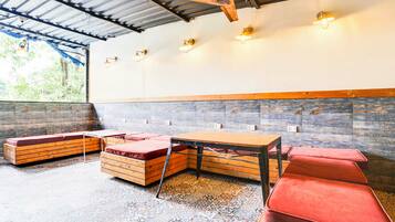 Interior de restaurante con techo alto, vigas a la vista y una variedad de opciones de asientos, incluyendo bancos y una mesa.