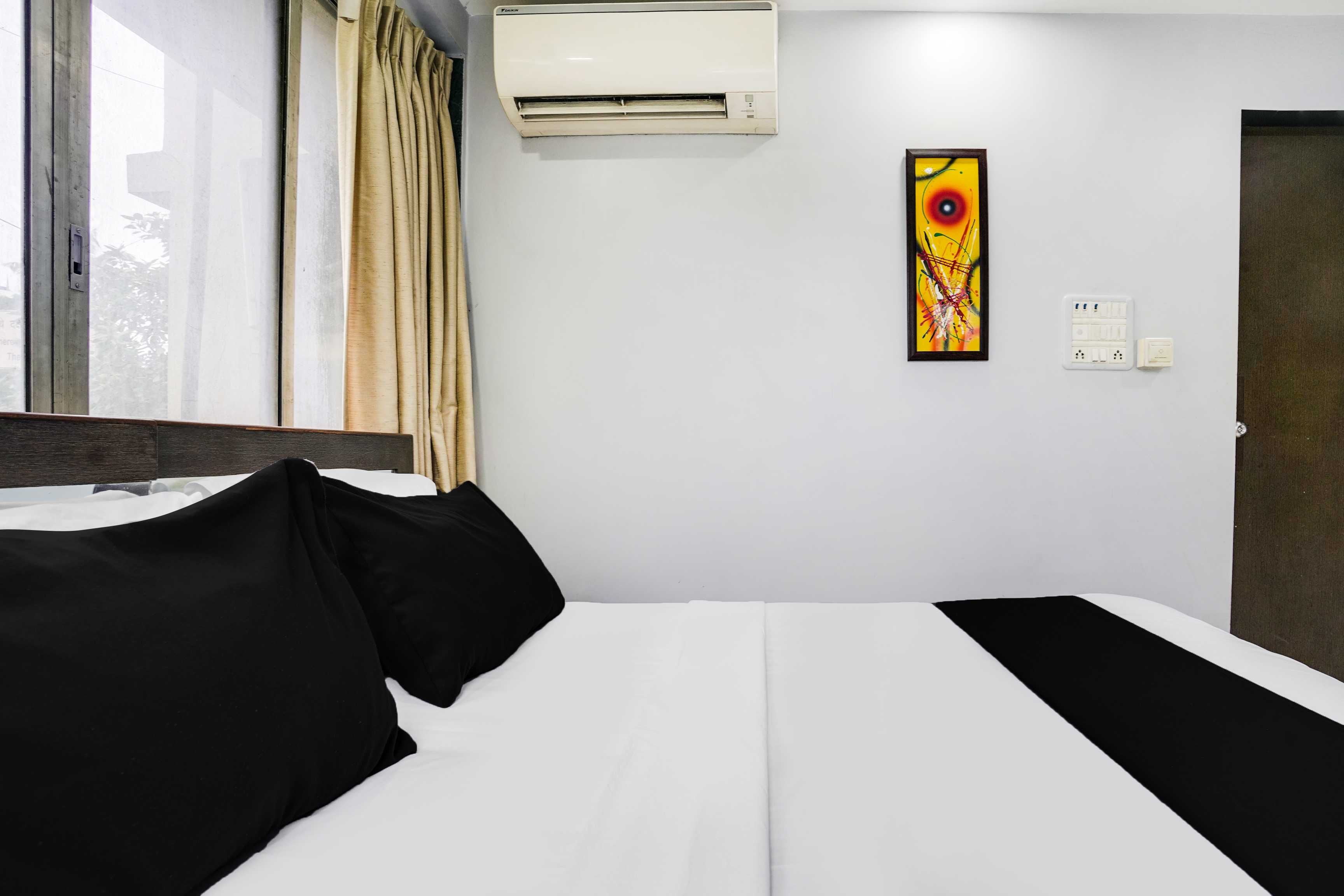 Ein Hotelzimmer mit Bett, Klimaanlage, einem Gemälde und einer Tür.
