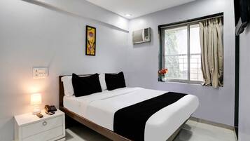 Una habitación de hotel moderna con cama, mesita de noche, lámpara, equipo de aire acondicionado y ventana con cortinas.