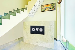 Una escalera con piso de mármol que lleva a un rellano con un cartel que dice 'OYO'.
