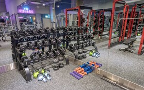 Un gimnasio con diverso equipamiento de levantamiento de pesas, incluyendo mancuernas y kettelbells.