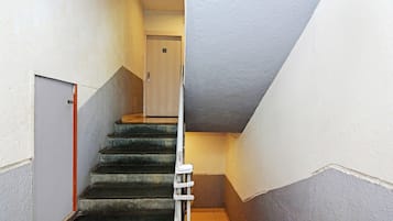 A narrow stairway with a handrail, leading to a door at the top.