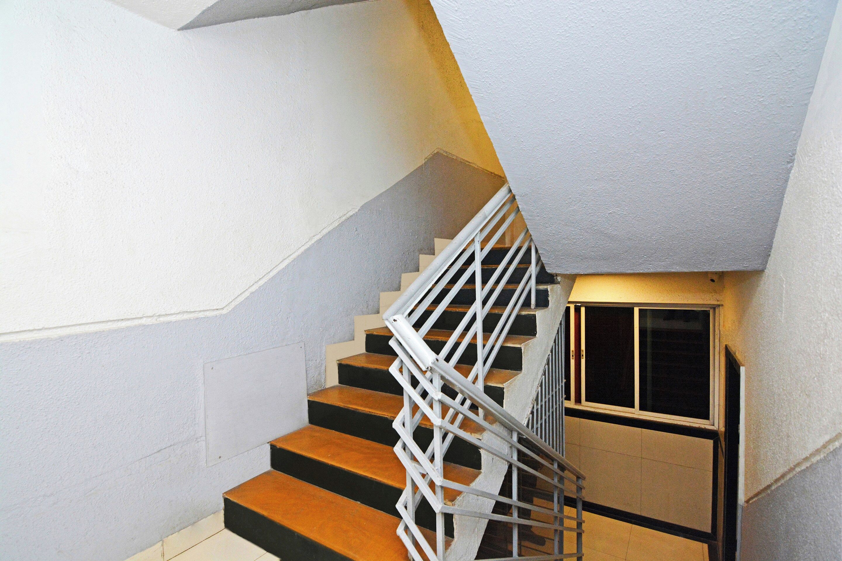 Una escalera con barandilla blanca y un rellano en la esquina.