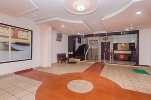 A hotel lobby with a reception desk, a staircase, and a seating area. - Hotel O Gems (Mumbai)