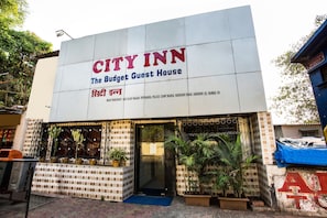 Letrero de CITY INN con el nombre de una casa de huéspedes, una reja metálica y plantas en macetas al frente.