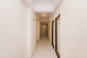 Un pasillo de hotel con puertas a la derecha, piso de color claro e iluminación empotrada en el techo.