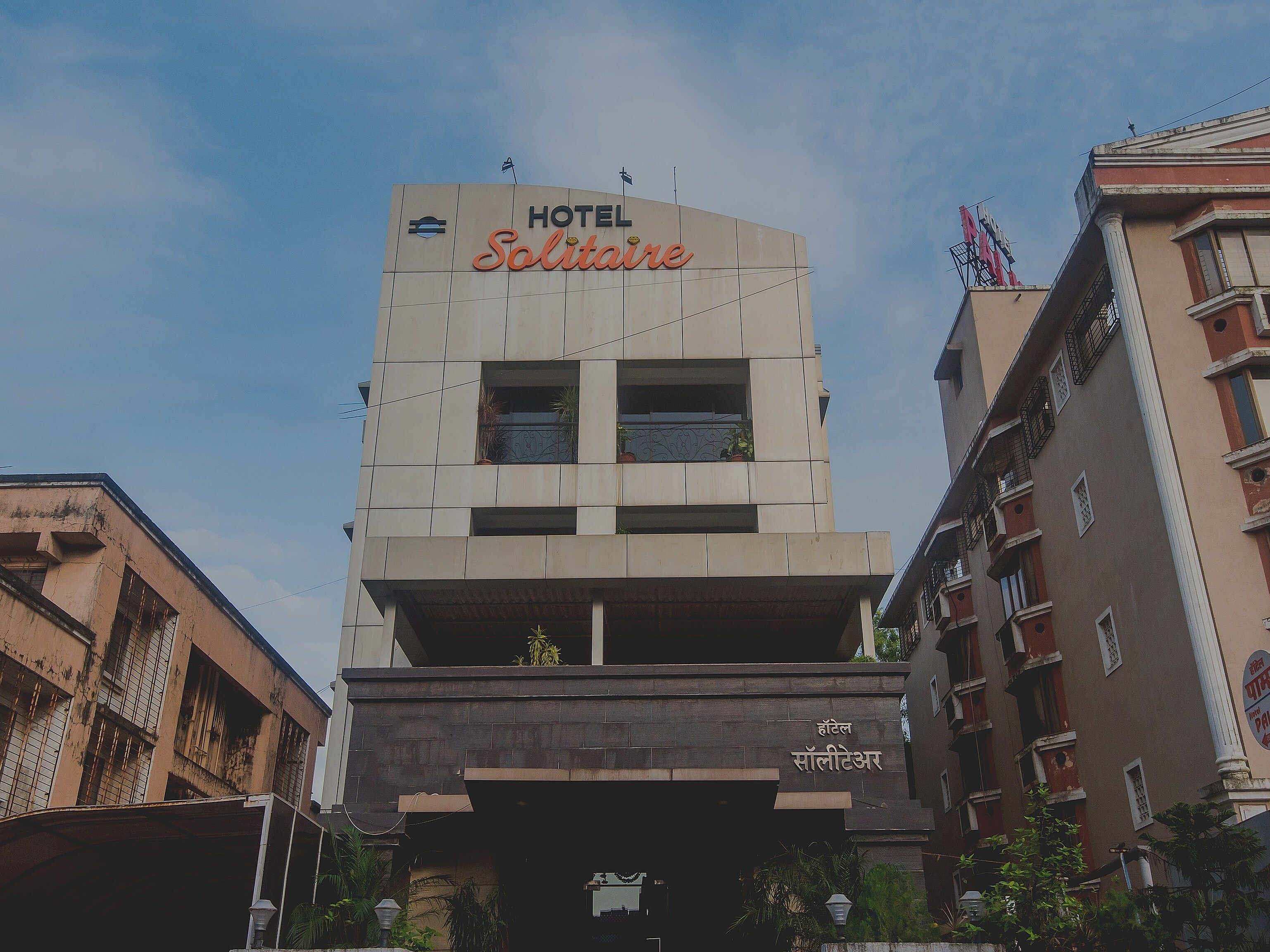 Un hotel llamado 'Solitaire' con una fachada moderna, una entrada destacada y una bandera en la parte superior.